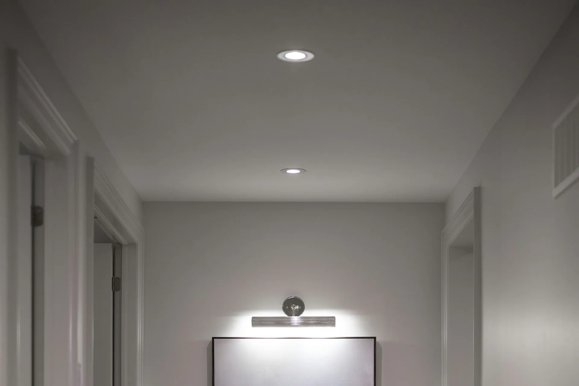 Recessed ceiling lights and a picture light in a residential hallway